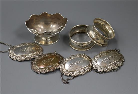 A set of three modern silver wine labels, one other silver wine label, two silver napkin rings and a silver salt.